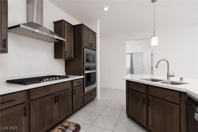 kitchen with stainless steel appliances, wall chimney range hood, a sink, dark brown cabinets, and light countertops