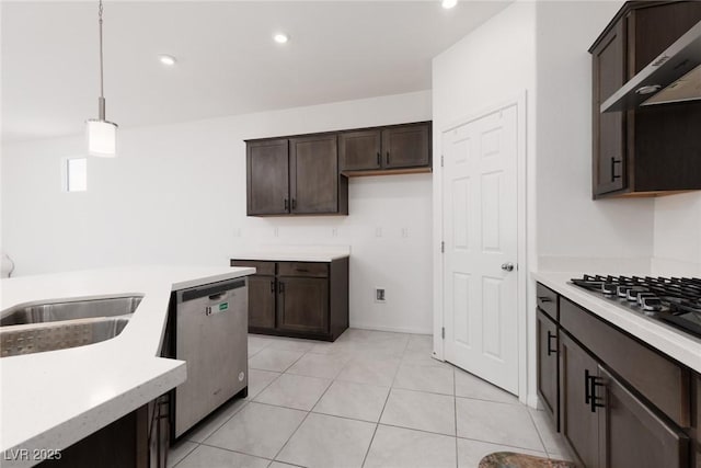 kitchen with appliances with stainless steel finishes, wall chimney exhaust hood, dark brown cabinets, light countertops, and decorative light fixtures