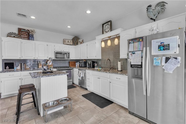 7929 Ben Hogan Dr, Las Vegas, NV 89149 - kitchen featuring appliances with stainless steel finishes, dark stone counters, a sink, tasteful backsplash, and white cabinets