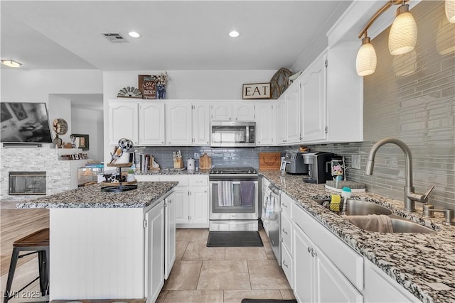 7929 Ben Hogan Dr, Las Vegas, NV 89149 - kitchen featuring stainless steel appliances, a sink, stone counters, tasteful backsplash, and white cabinetry
