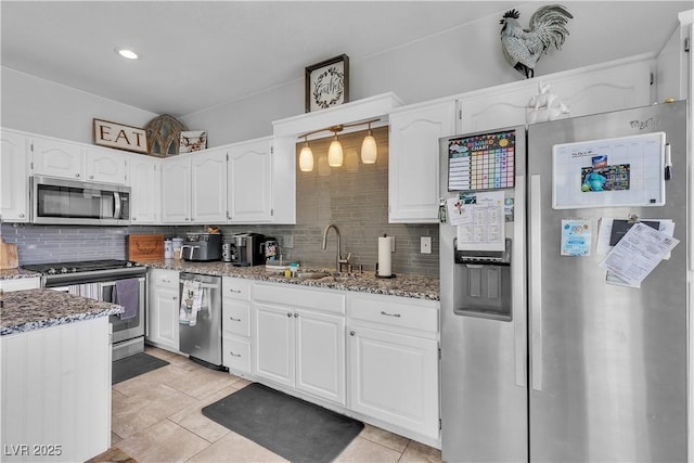 7929 Ben Hogan Dr, Las Vegas, NV 89149 - kitchen with stainless steel appliances, a sink, stone counters, backsplash, and white cabinetry