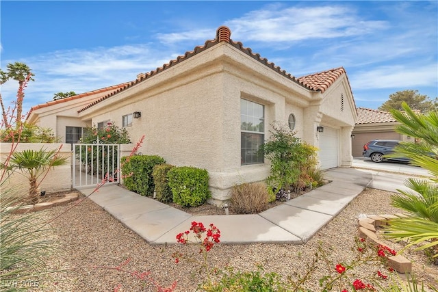 7929 Ben Hogan Dr, Las Vegas, NV 89149 - view of side of home with a garage, stucco siding, a tile roof, and a gate