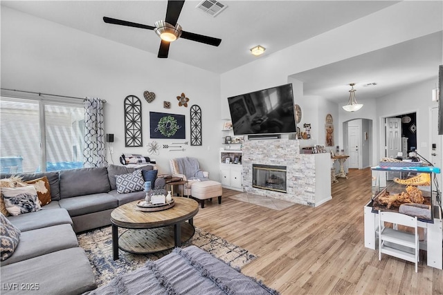 7929 Ben Hogan Dr, Las Vegas, NV 89149 - living area with arched walkways, light wood finished floors, a ceiling fan, and a stone fireplace