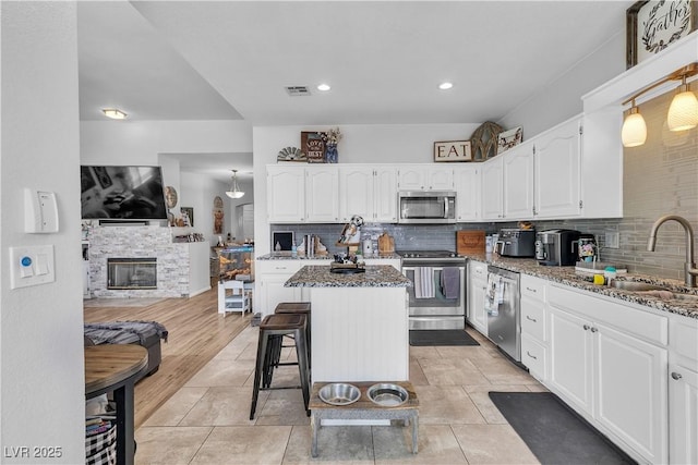7929 Ben Hogan Dr, Las Vegas, NV 89149 - kitchen with stainless steel appliances, a sink, dark stone countertops, white cabinetry, and decorative backsplash
