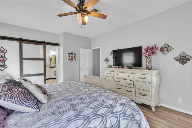 7929 Ben Hogan Dr, Las Vegas, NV 89149 - bedroom with light wood-type flooring, a barn door, baseboards, a ceiling fan, and connected bathroom