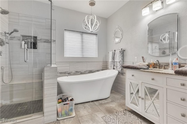 7929 Ben Hogan Dr, Las Vegas, NV 89149 - full bathroom featuring a shower stall, vanity, a freestanding bath, a chandelier, and tile walls