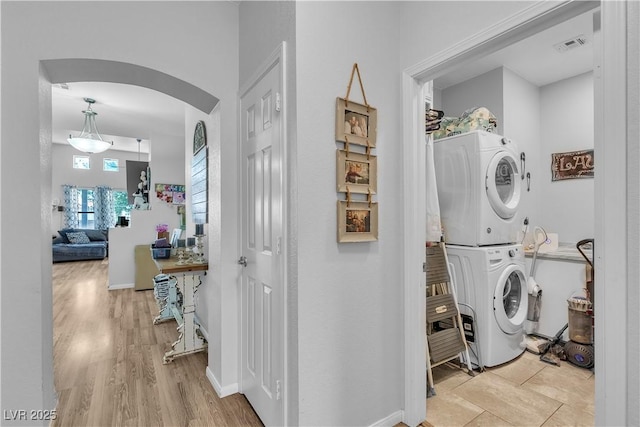 7929 Ben Hogan Dr, Las Vegas, NV 89149 - laundry area with stacked washing machine and dryer, arched walkways, baseboards, and light wood-type flooring