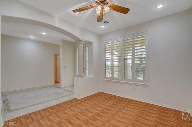 10302 Cara Mia Ct, Las Vegas, NV 89135 - empty room with ornate columns, arched walkways, a ceiling fan, light wood finished floors, and baseboards