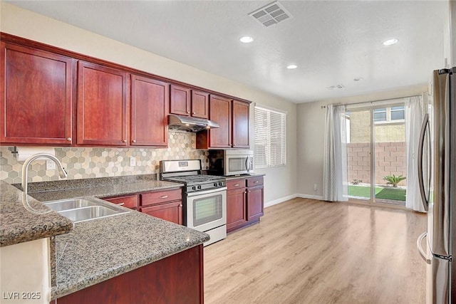 248 Windmill Croft Dr, Las Vegas, NV 89148 - kitchen with stainless steel appliances, reddish brown cabinets, under cabinet range hood, a sink, and baseboards