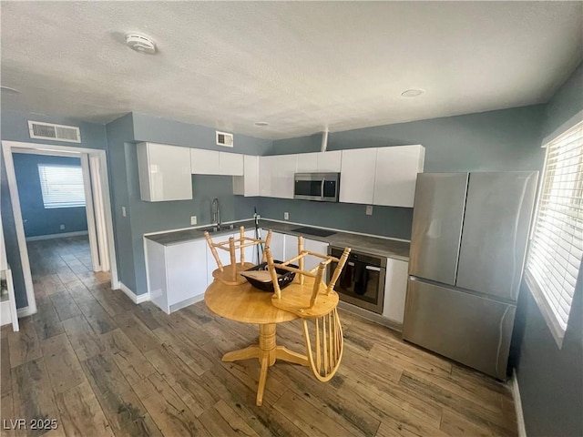 501 S Maryland Pkwy Unit C17, Las Vegas, NV 89101 - kitchen featuring appliances with stainless steel finishes, white cabinets, wood finished floors, a sink, and baseboards