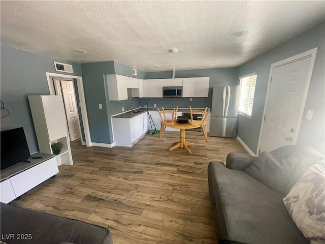 501 S Maryland Pkwy Unit C17, Las Vegas, NV 89101 - kitchen with appliances with stainless steel finishes, dark wood-type flooring, white cabinetry, baseboards, and a textured ceiling