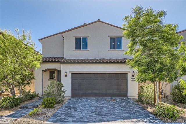 view of front of house with a tiled roof, stucco siding, a garage, and decorative driveway