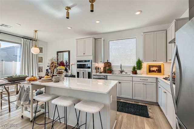 kitchen featuring appliances with stainless steel finishes, a sink, healthy amount of natural light, a kitchen breakfast bar, and recessed lighting
