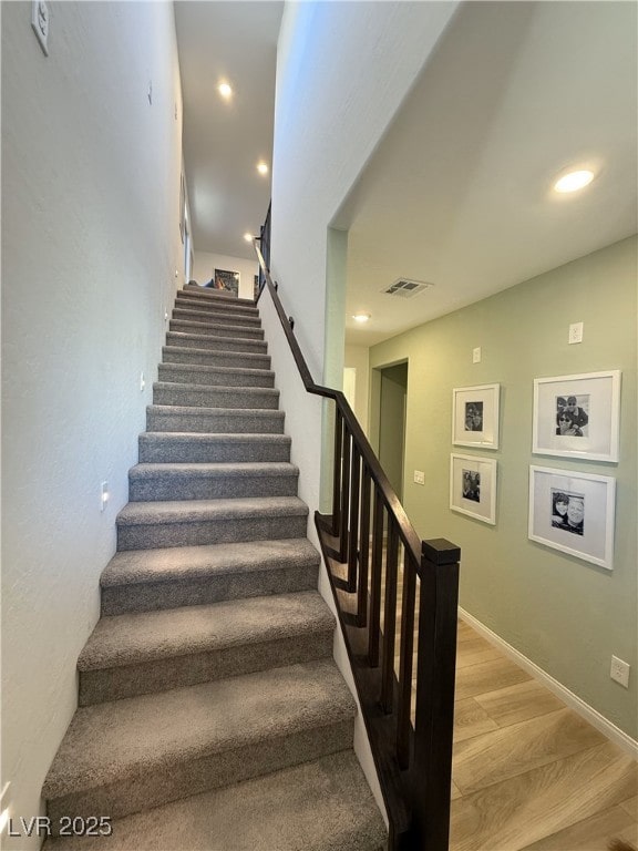 stairway featuring wood finished floors and recessed lighting