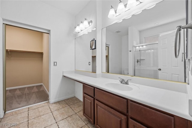 full bathroom featuring a stall shower, tile patterned floors, vanity, a spacious closet, and baseboards