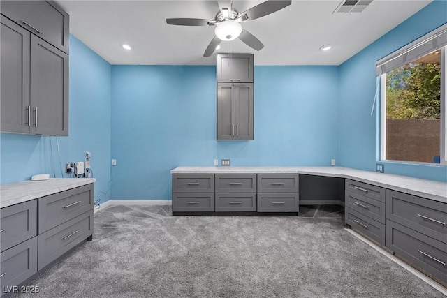 unfurnished office with light colored carpet, ceiling fan, baseboards, built in desk, and recessed lighting