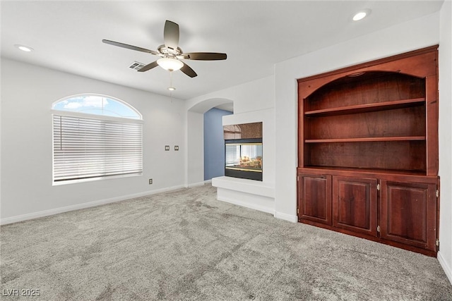 unfurnished living room featuring carpet floors, ceiling fan, plenty of natural light, arched walkways, and recessed lighting
