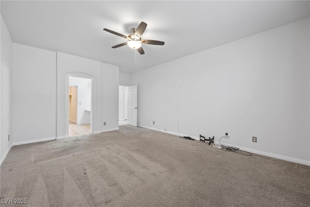 unfurnished bedroom with carpet floors, baseboards, arched walkways, connected bathroom, and a ceiling fan