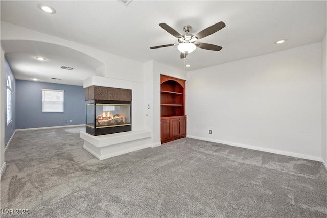 unfurnished living room with carpet flooring, a multi sided fireplace, baseboards, a ceiling fan, and recessed lighting