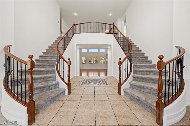 foyer entrance featuring stairs, light tile patterned floors, a high ceiling, recessed lighting, and baseboards