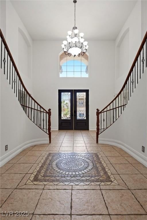 foyer featuring stairway, a chandelier, a high ceiling, french doors, and baseboards