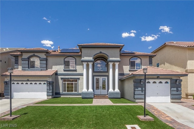 mediterranean / spanish-style house with french doors, concrete driveway, a front lawn, and solar panels