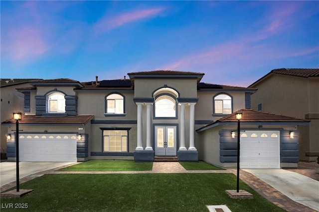mediterranean / spanish house featuring french doors, concrete driveway, a front lawn, solar panels, and stucco siding