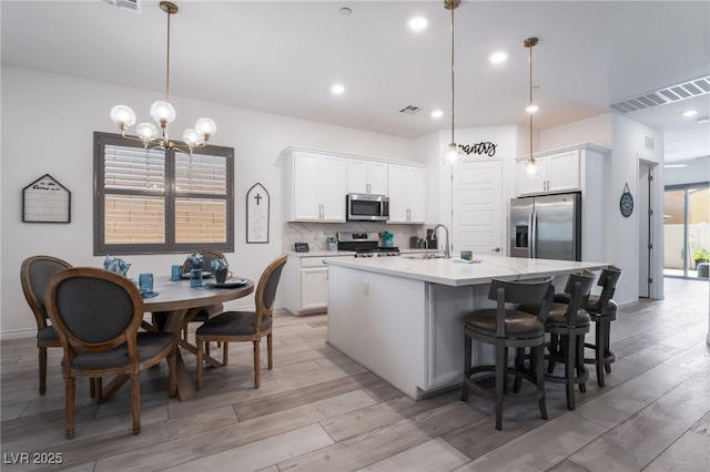 778 Dainty Daffodil St, Henderson, NV 89011 - kitchen featuring appliances with stainless steel finishes, light wood-type flooring, a kitchen island with sink, backsplash, and recessed lighting