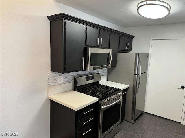 7885 W Flamingo Rd Unit 2019, Las Vegas, NV 89147 - kitchen with stainless steel appliances, light countertops, dark cabinetry, and backsplash