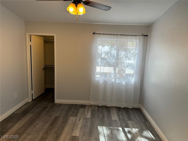 7885 W Flamingo Rd Unit 2019, Las Vegas, NV 89147 - unfurnished bedroom featuring dark wood-style floors, baseboards, a walk in closet, and a ceiling fan
