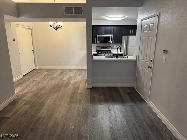 7885 W Flamingo Rd Unit 2019, Las Vegas, NV 89147 - kitchen with stainless steel appliances, dark cabinetry, dark wood-style floors, a chandelier, and baseboards
