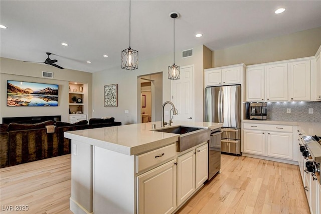 kitchen with appliances with stainless steel finishes, a sink, light wood-style floors, a ceiling fan, and recessed lighting