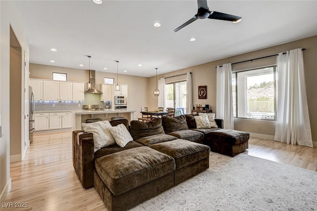 living room with light wood-style floors, a ceiling fan, recessed lighting, and baseboards