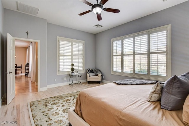 bedroom featuring multiple windows, wood finished floors, baseboards, and a ceiling fan