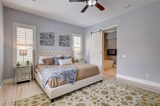bedroom with a barn door, wood finished floors, baseboards, and ceiling fan