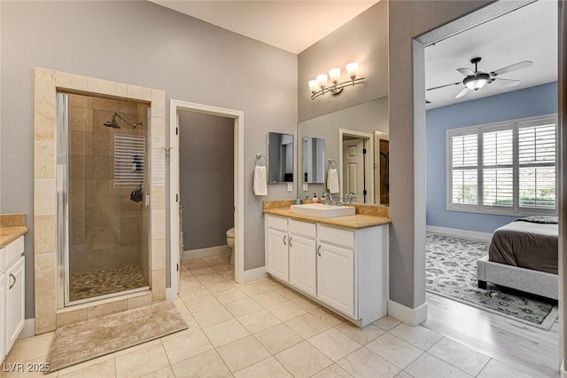 full bath featuring a stall shower, vanity, baseboards, toilet, and ceiling fan