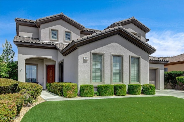 mediterranean / spanish home with a garage, a front lawn, stucco siding, concrete driveway, and a tiled roof