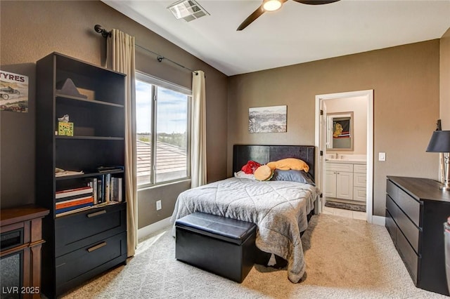 bedroom featuring light carpet, baseboards, ensuite bath, and ceiling fan