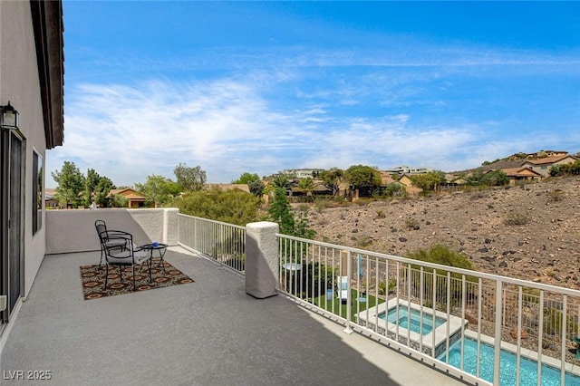 balcony with view of pool and an in-ground hot tub