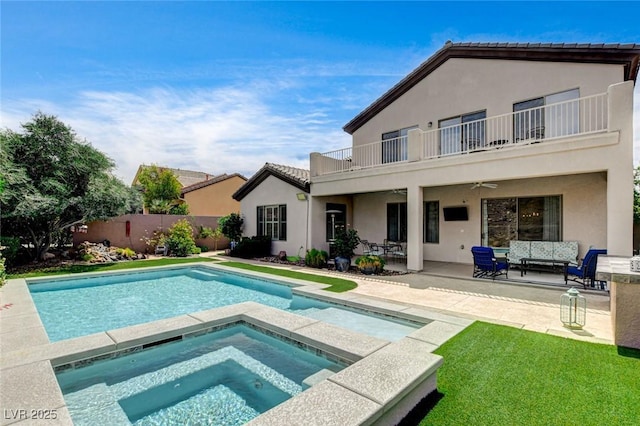 rear view of house with a balcony, an outdoor hangout area, a ceiling fan, an in-ground hot tub, and a patio area