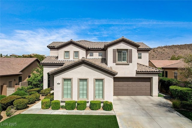 mediterranean / spanish house featuring stucco siding, a garage, driveway, and a tile roof