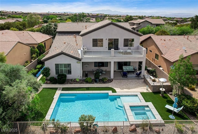 rear view of house featuring a balcony, a fenced backyard, a pool with connected hot tub, outdoor lounge area, and a patio area