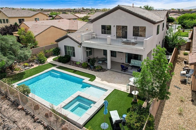 back of property with a balcony, stucco siding, a patio area, and a tile roof