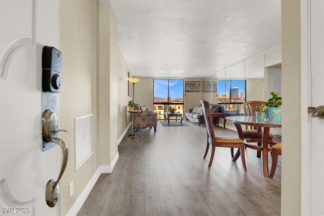 3930 University Center Dr Unit 603, Las Vegas, NV 89119 - dining room featuring wood finished floors, baseboards, a textured ceiling, and a wall of windows