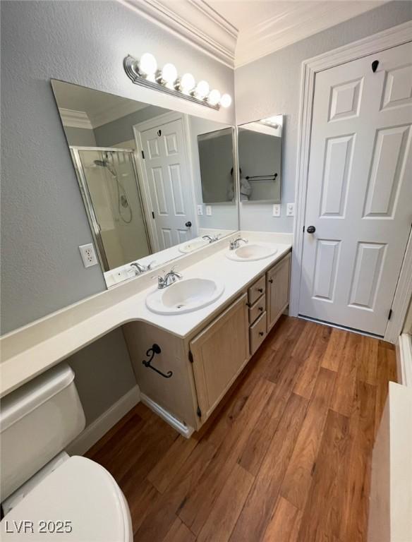 5165 Briar Meadow Way, Las Vegas, NV 89118 - bathroom featuring wood finished floors, a stall shower, crown molding, toilet, and double vanity