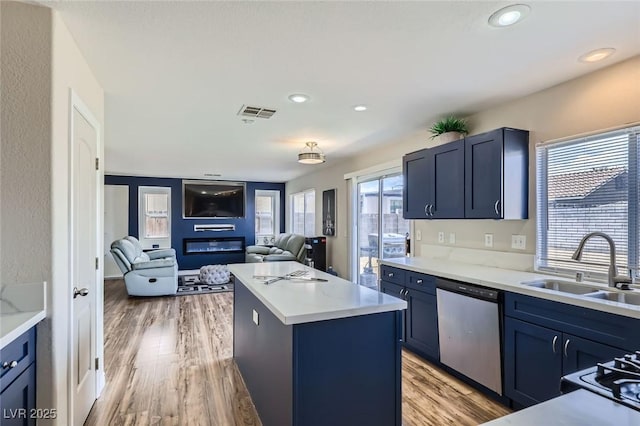5502 Cinnamon Ave, Las Vegas, NV 89122 - kitchen with stainless steel dishwasher, a sink, a kitchen island, open floor plan, and blue cabinetry