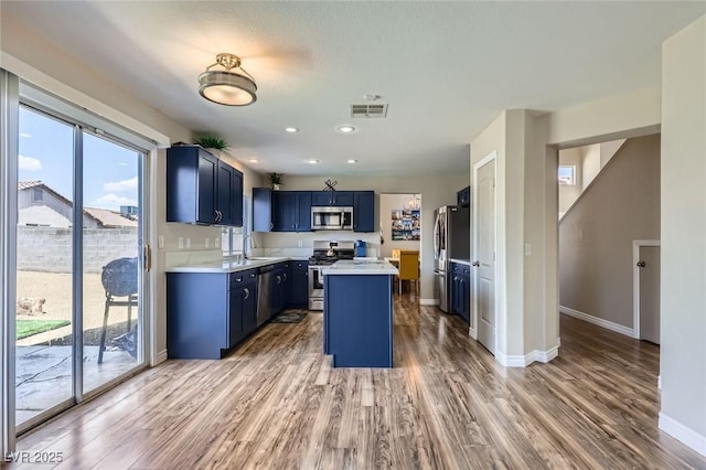 5502 Cinnamon Ave, Las Vegas, NV 89122 - kitchen with stainless steel appliances, blue cabinets, light countertops, light wood finished floors, and recessed lighting