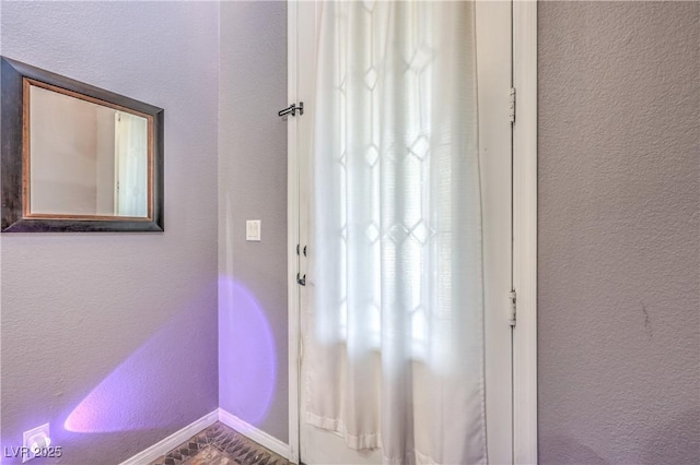 doorway with a textured wall and baseboards