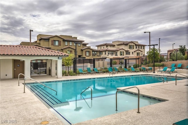 community pool featuring fence, a patio area, and a residential view