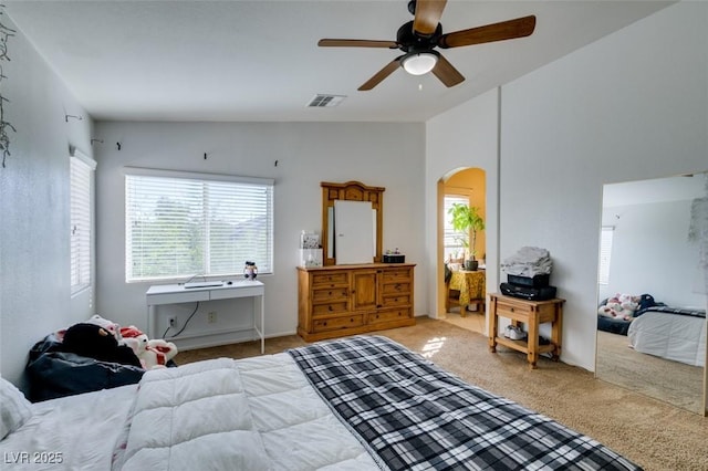 carpeted bedroom with arched walkways, lofted ceiling, and ceiling fan